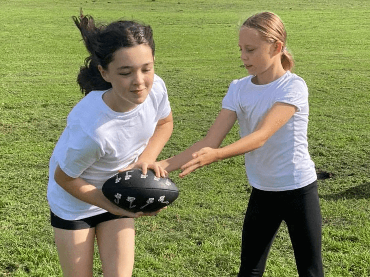 Two girls passing the ball while playing JagTag.