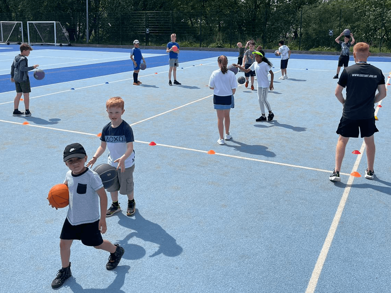 Children playing ball games at a holiday club on tennis courts.