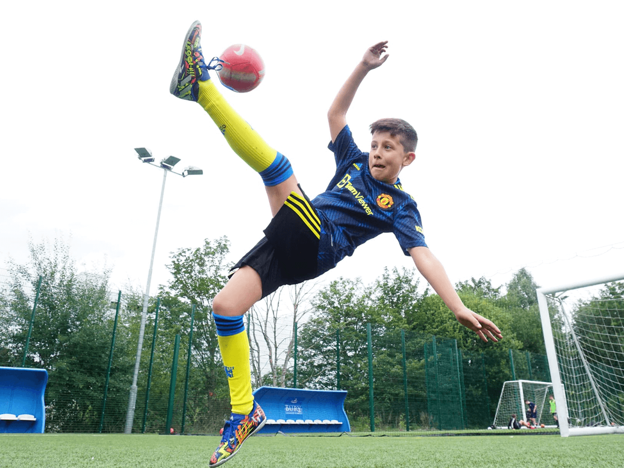 A boy performing an overhead kick at a football camp.
