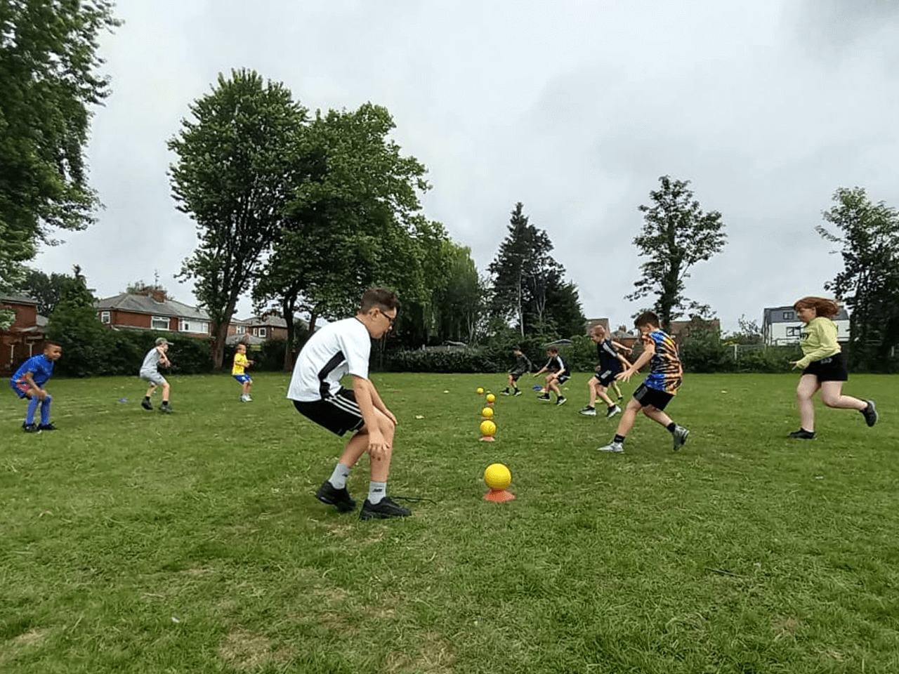 A group of boys and girls starting a game of dodgeball on a sports field.