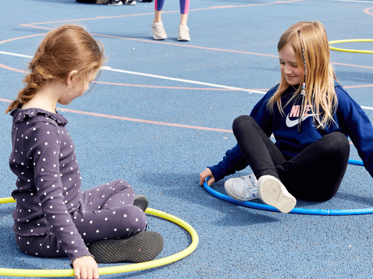 Two girls sat in their hoops on the playground floor.