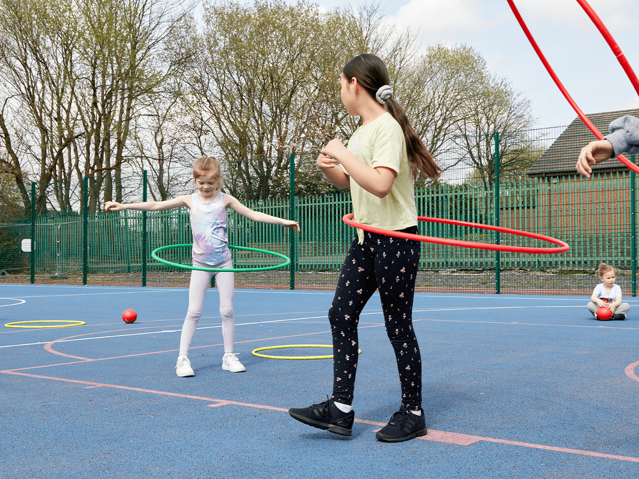 Two girls hula hooping in the playground.