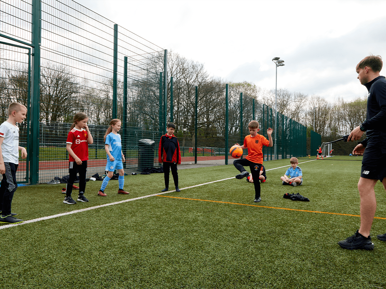 Group of children practicing keepy-uppies with a coach.