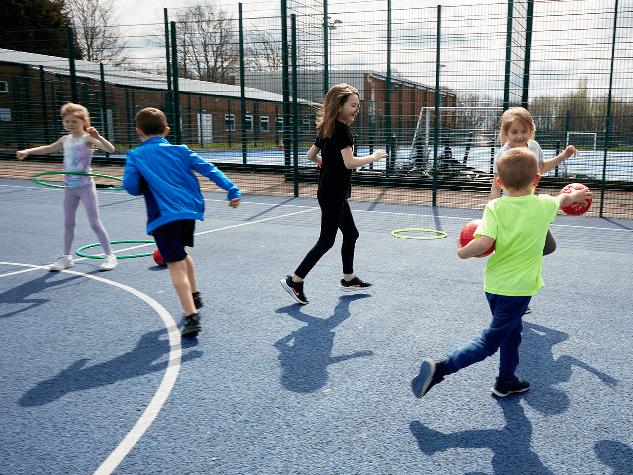 Children running around the playground at a holiday club.