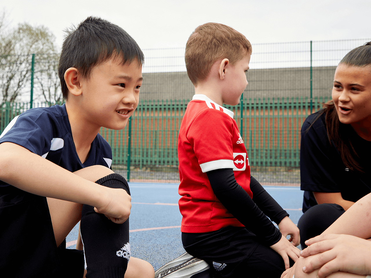 Two boys sat on the playground floor enjoying a break during a holiday club.