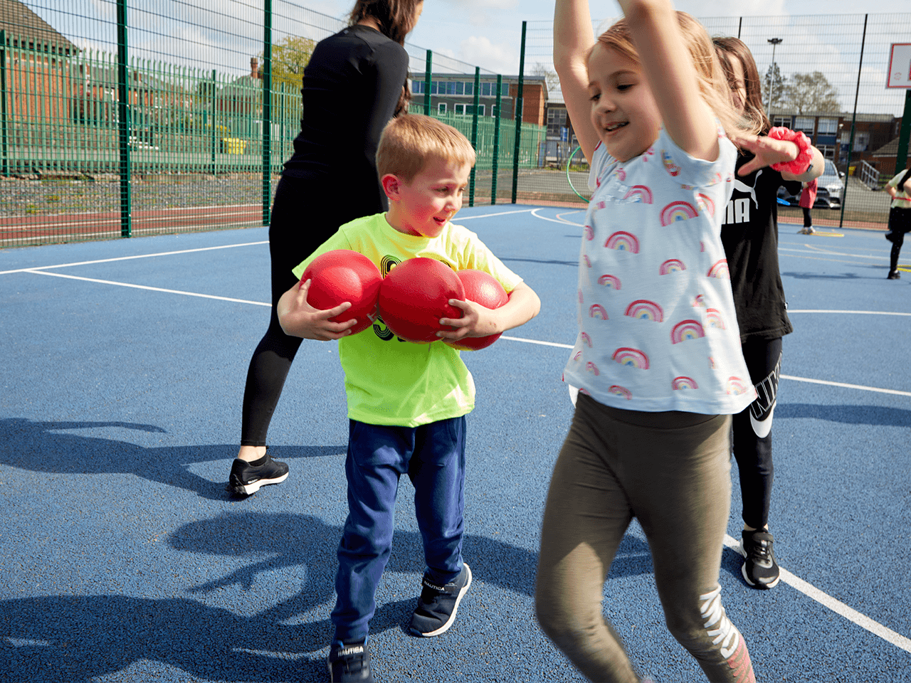 Happy children collecting balls at the end of a holiday club in the playground.