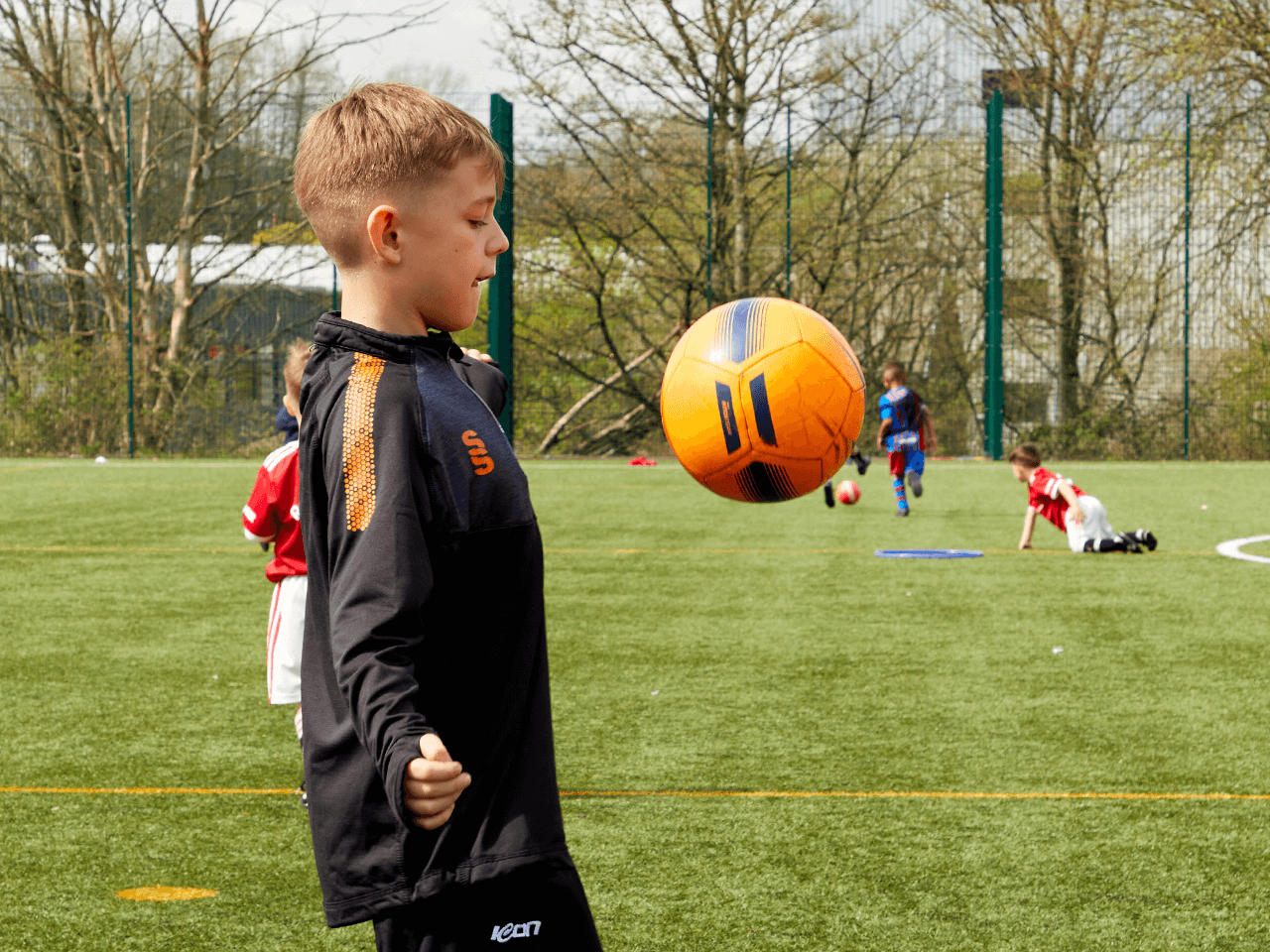 A boy controlling a football with his chest whilst doing keepy-ups.