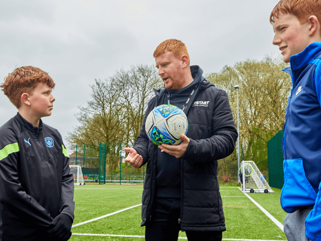 A coach giving football tips to two boys.