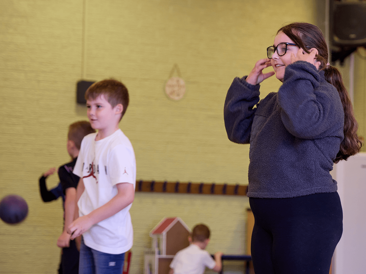 Children listening to instructions from a coach in the sports hall.