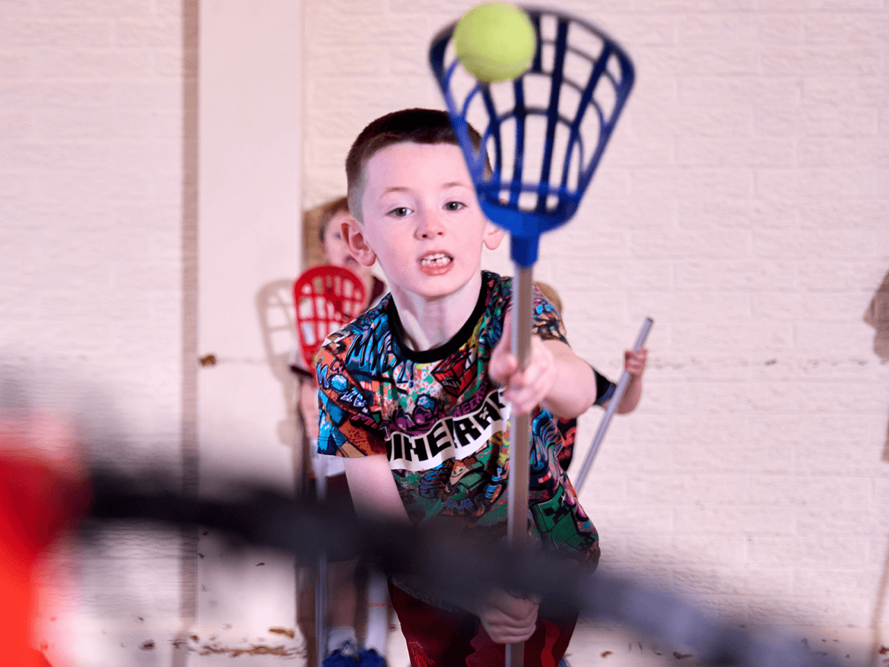 A boy throwing a ball with a lacrosse stick.