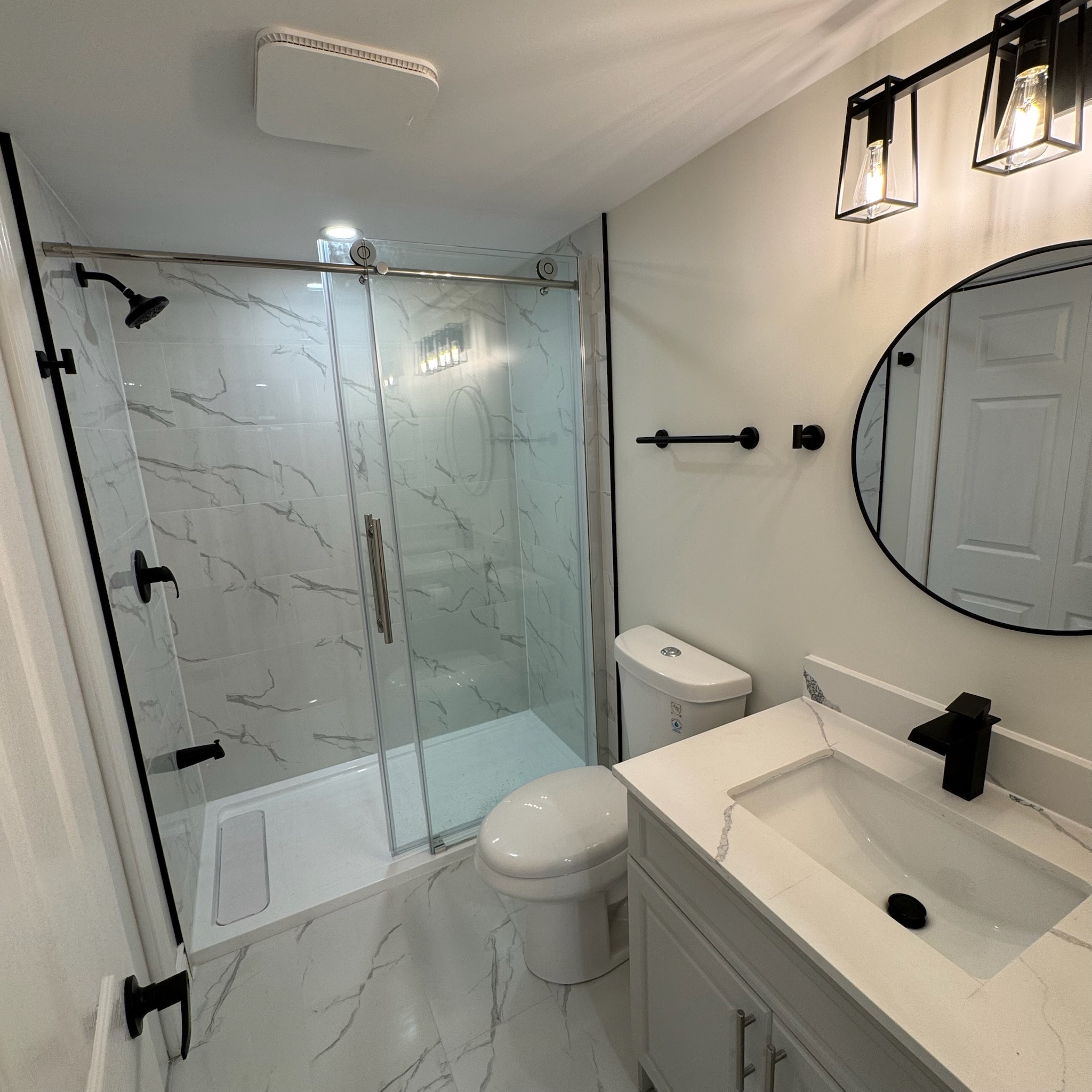 Bright living room with beige sectional sofa, round coffee table, fireplace with TV above, and armchair with yellow pillow beside built-in shelves.