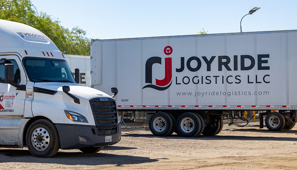 Parked semi trucks with the JoyRide Logistics LLC logo on the side of the truck container