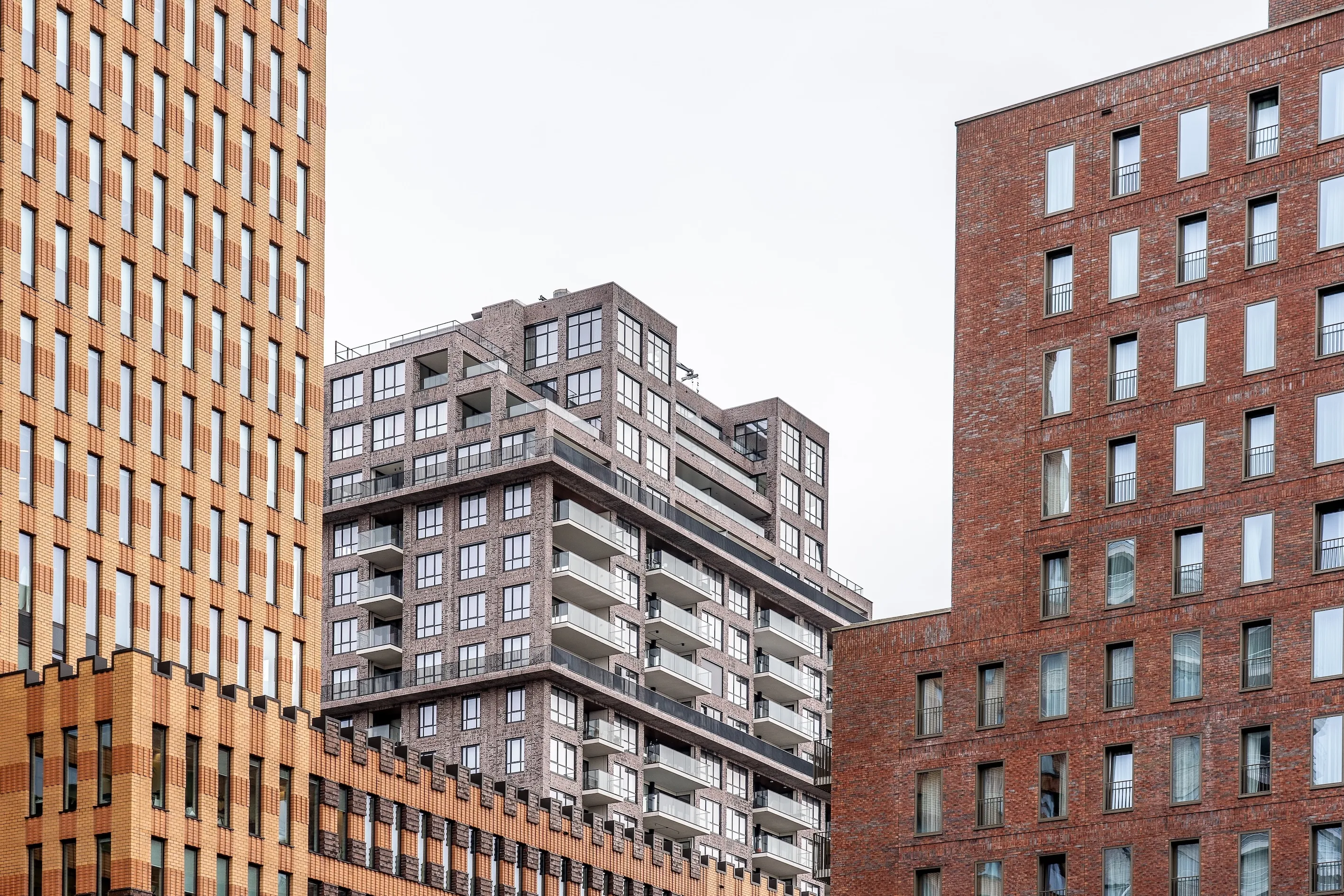 Modern multi-story residential buildings with large windows and balconies under an overcast sky.