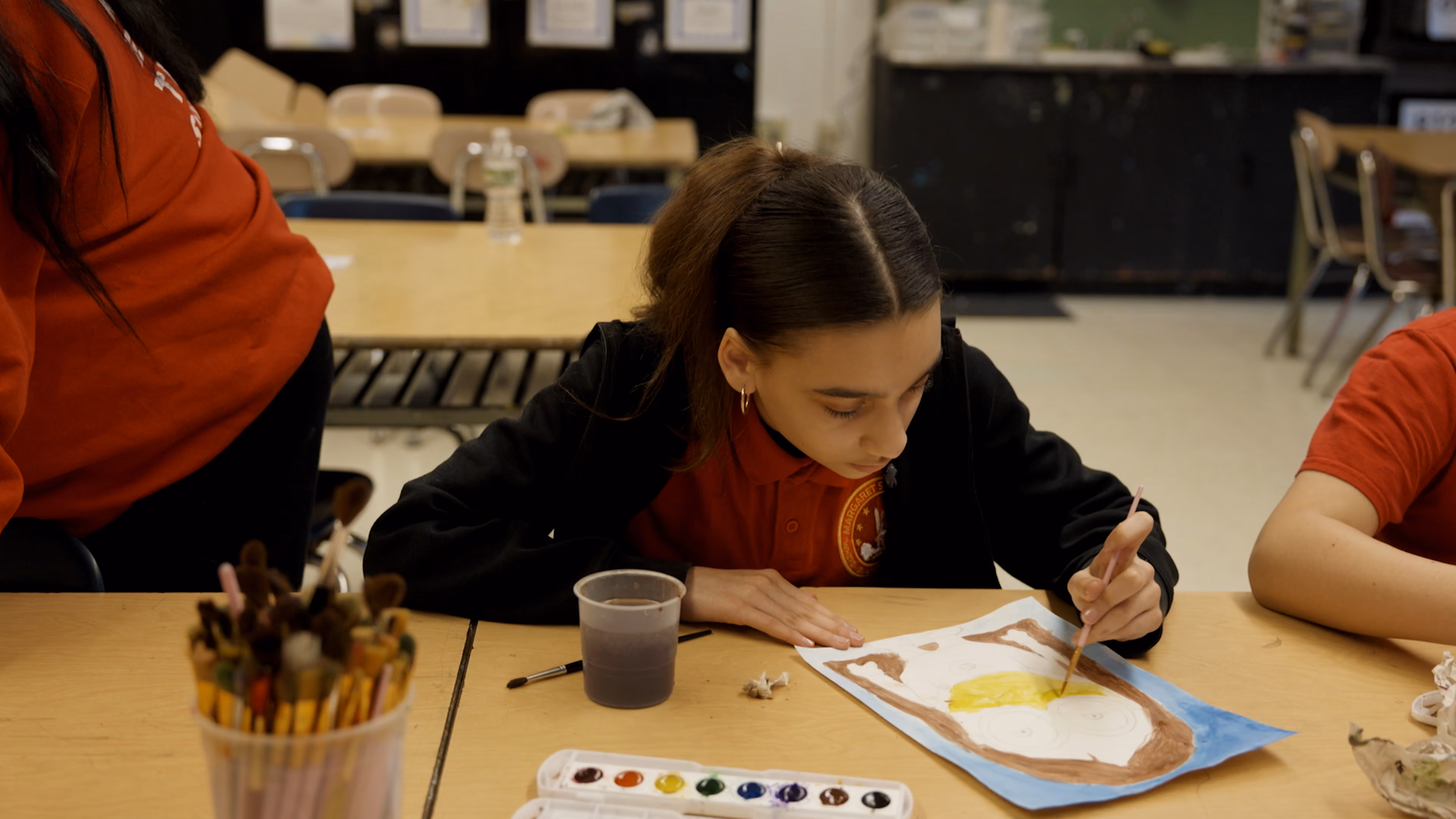 Student painting with watercolors during art class at school
