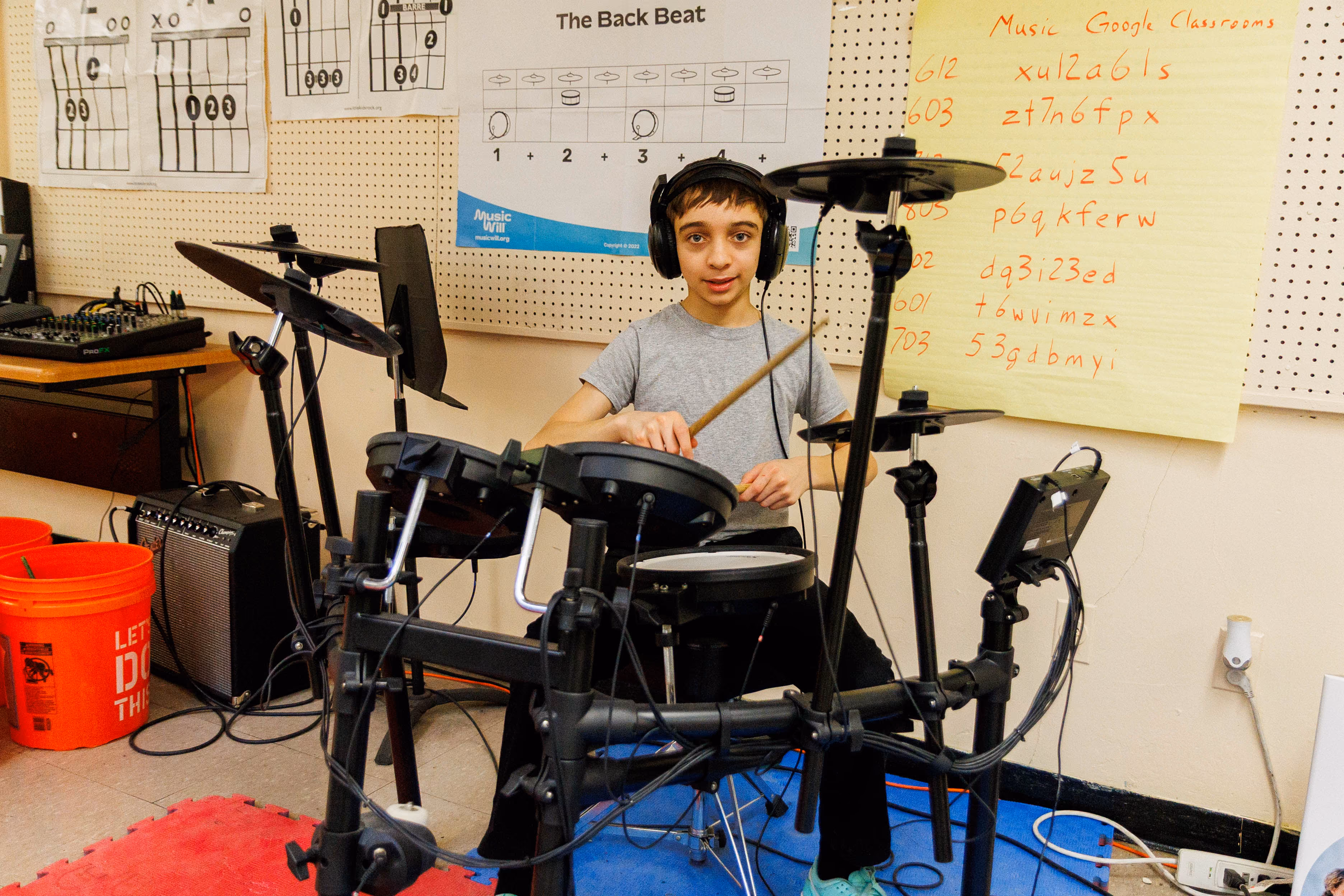 Student playing electronic drum kit in music classroom
