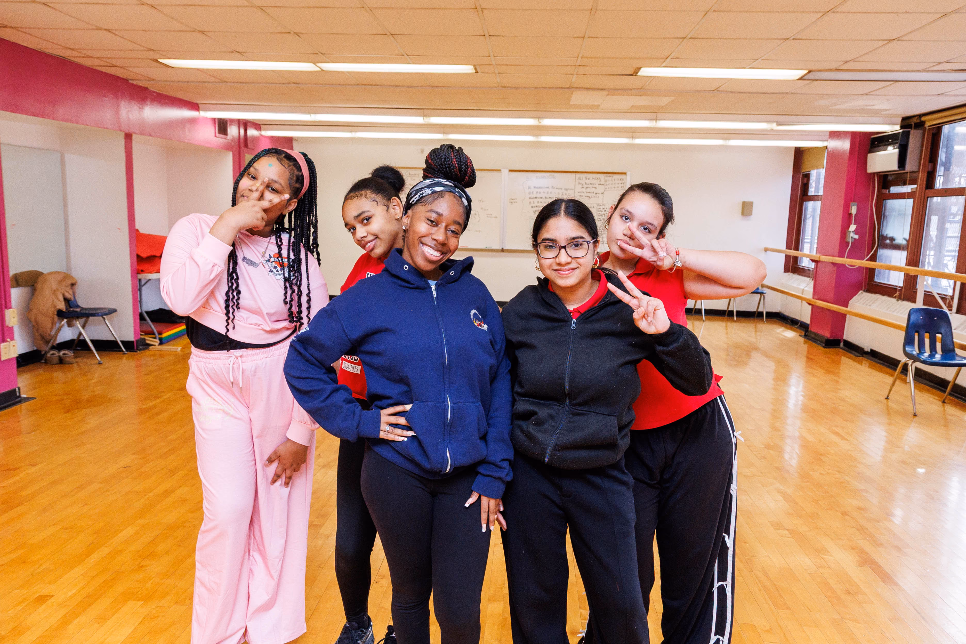 Five students posing together and smiling in a school dance studio