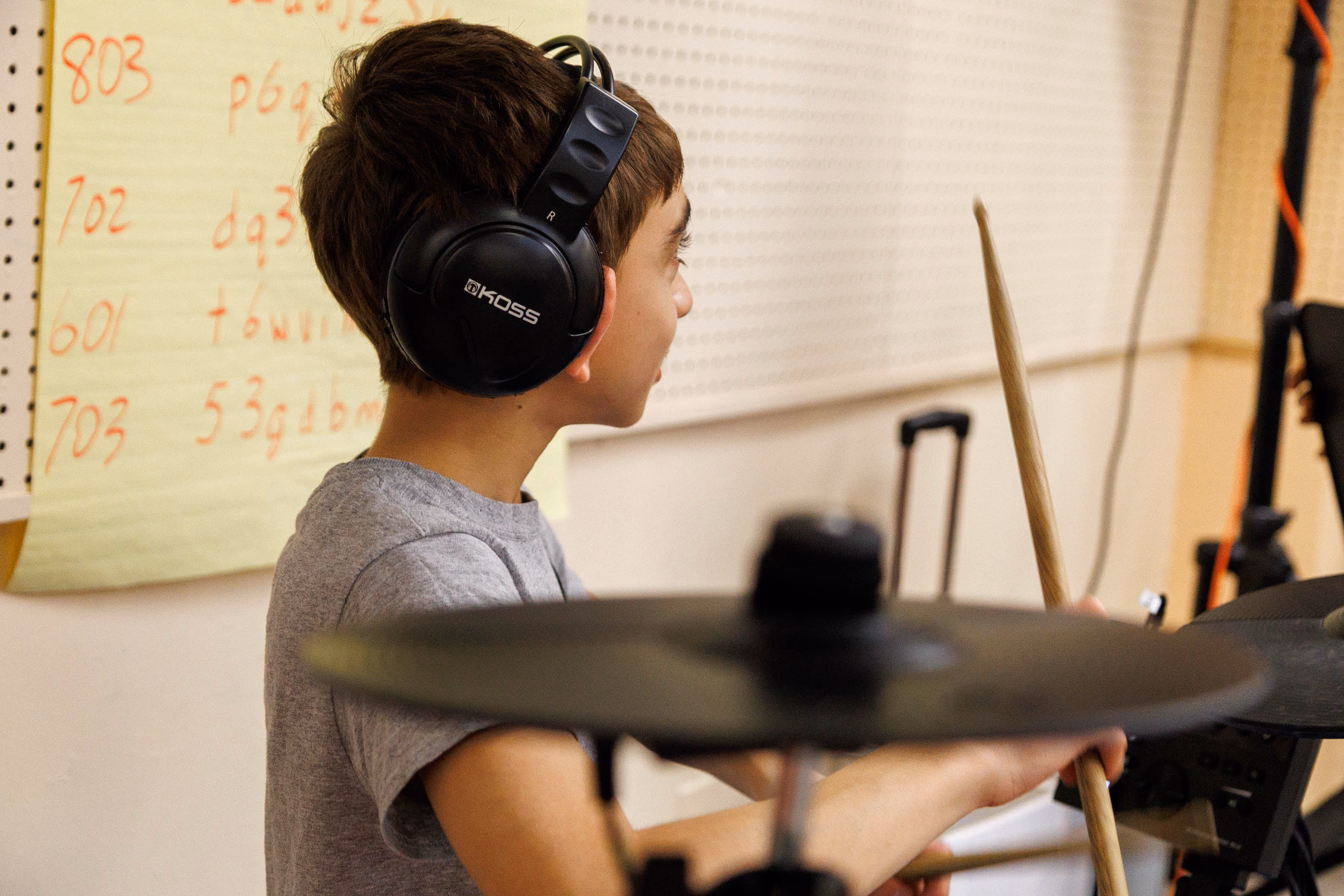 Student wearing headphones playing electronic drums in music class