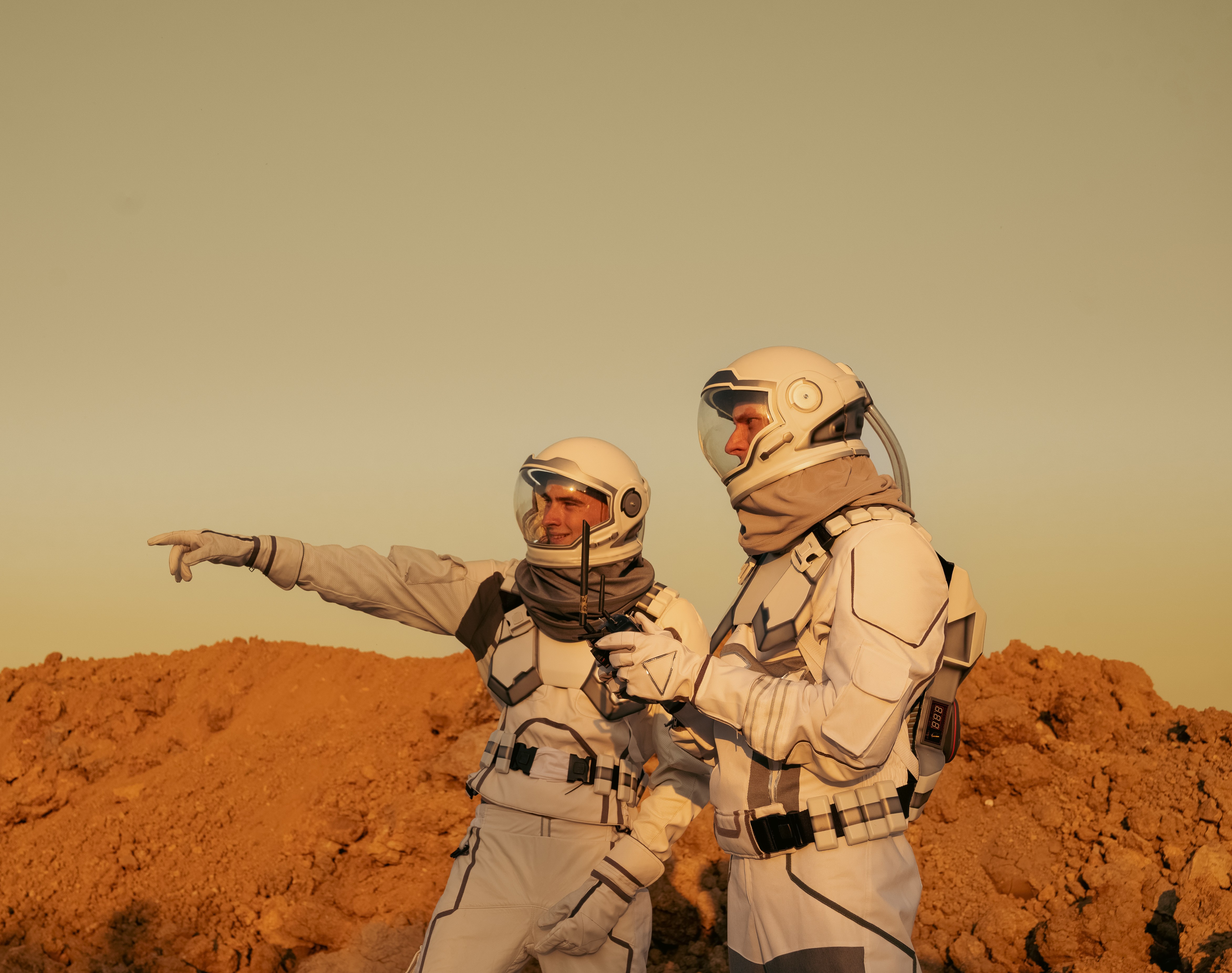 Two astronauts in spacesuits exploring a Mars-like desert terrain, representing human performance research in space analog environments