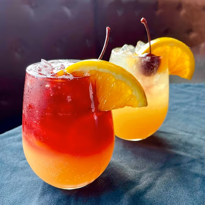 2 cocktails with an orange slice on top