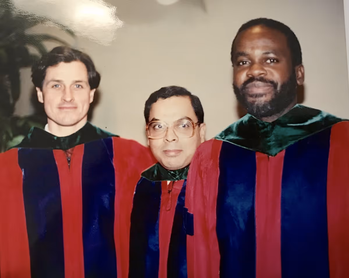 Black-and-white photo of seven medical professionals posing together, some wearing white coats and stethoscopes.