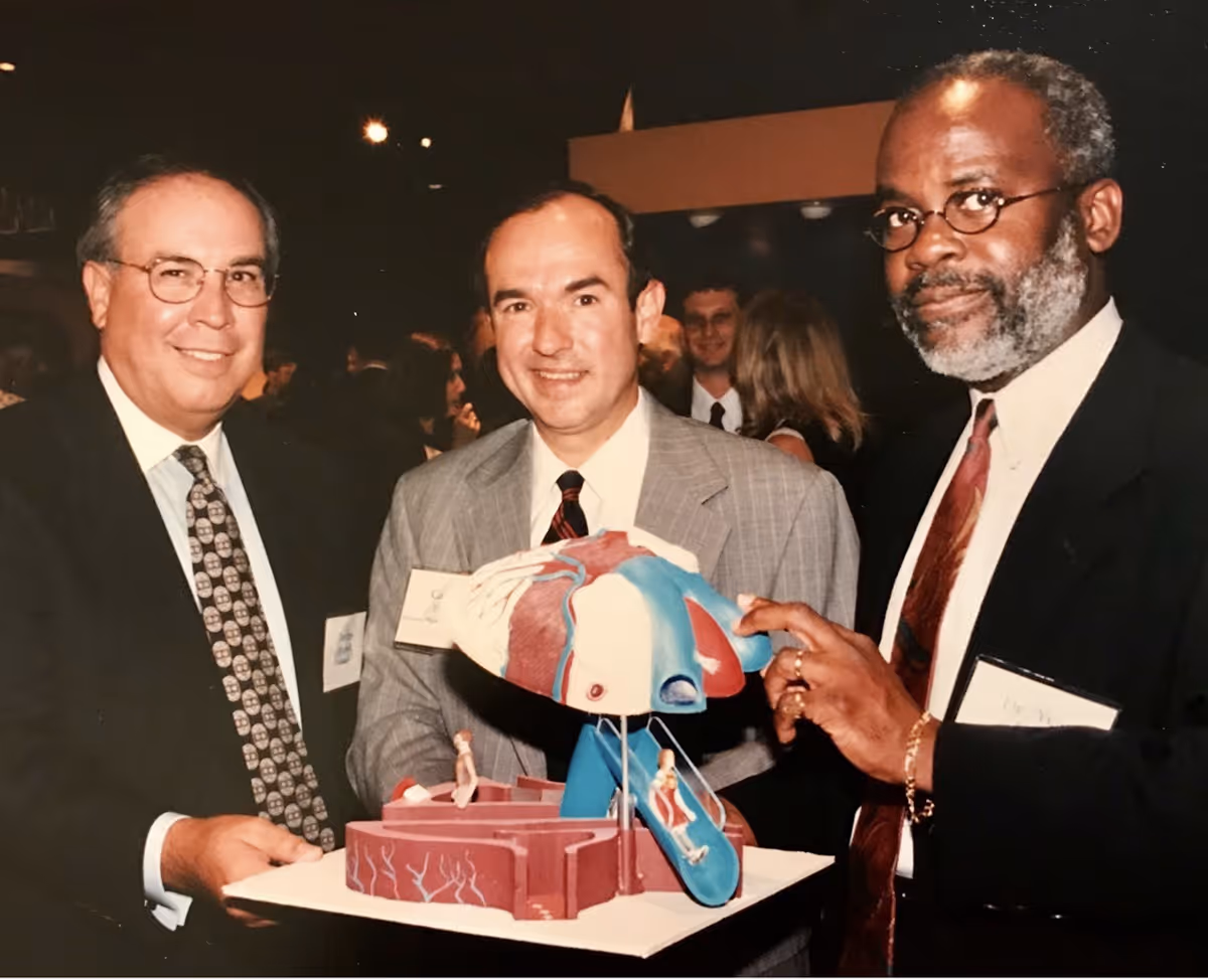 Black-and-white photo of seven medical professionals posing together, some wearing white coats and stethoscopes.