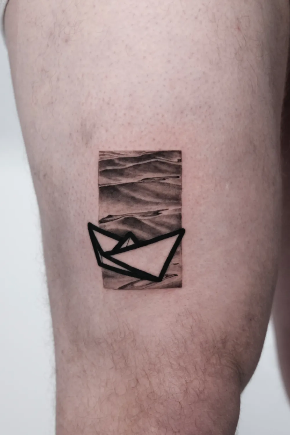 Fineline geometrisches Papierboot Tattoo an der Wade - Tattoo Artist Hamburg