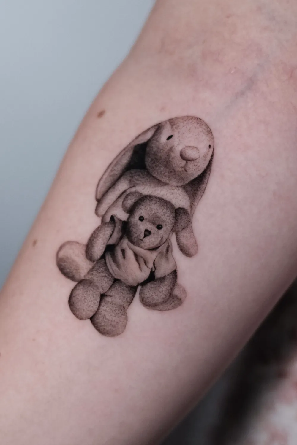 Feines realistisches Teddy Tattoo in Fine Line Technik, emotionales kleines Motiv gestochen von Tattoo Artist in Hamburg