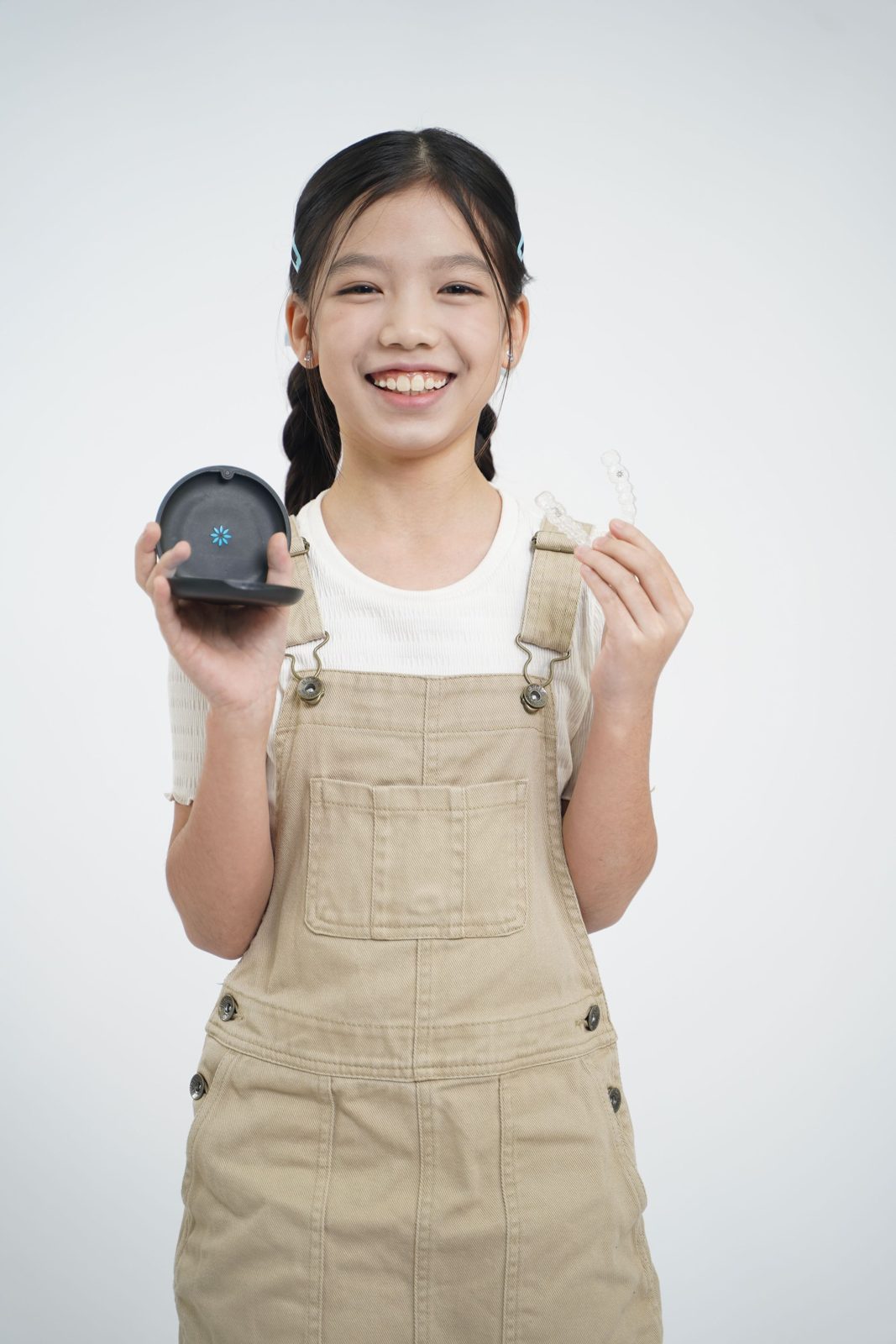 A smiling child holding a retainer and its case