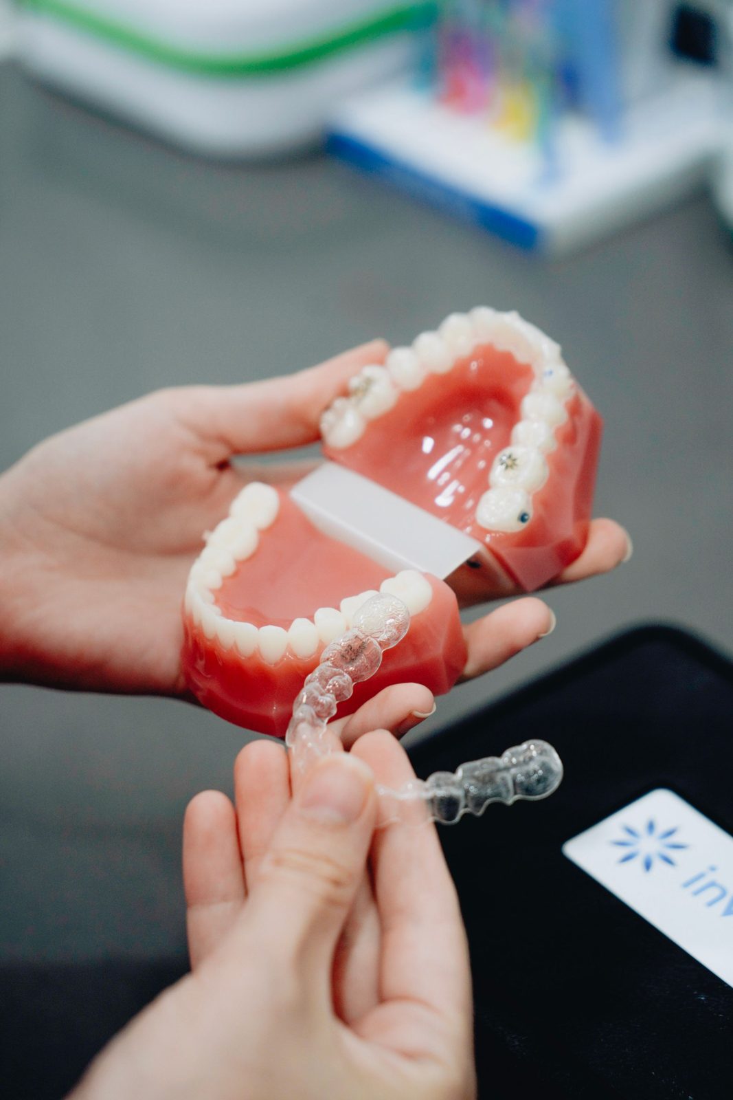 Hands holding a dental model and a clear aligner