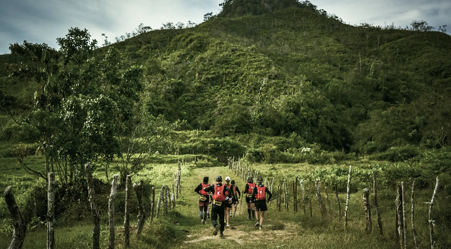 Expedition group running a farm track toward green hills in Antioquia, Colombia