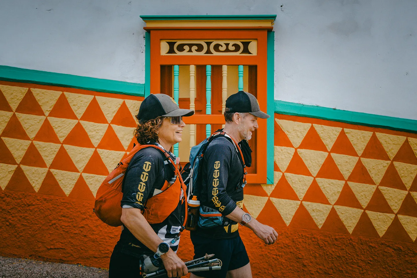 Charles and Mary Kate running past a brightly painted facade in a Colombian town