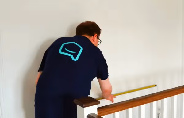 dwellow installer measuring a radiator on a staircase landing