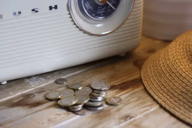 Pile of coins on a table in front of an art deco radio
