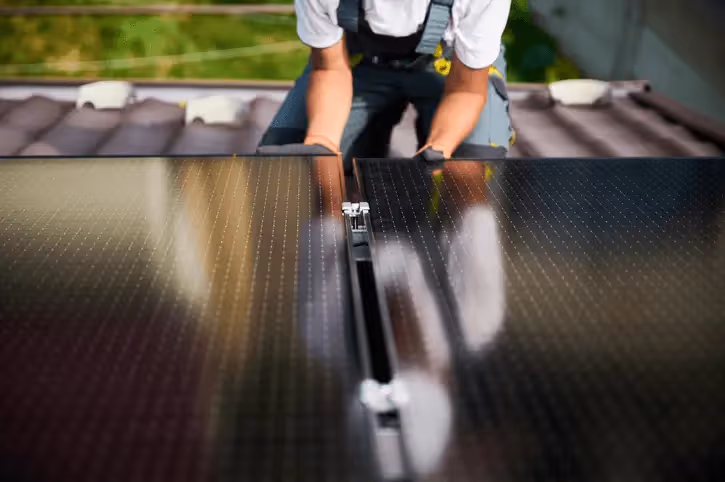 A solar installer on the roof of a house fitting panels