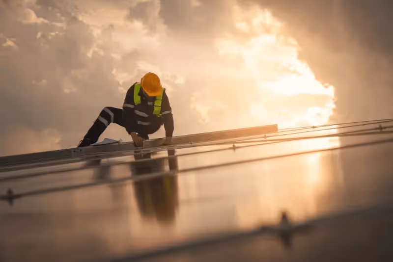 Engineer worker install solar panel on roof with sunset in the background