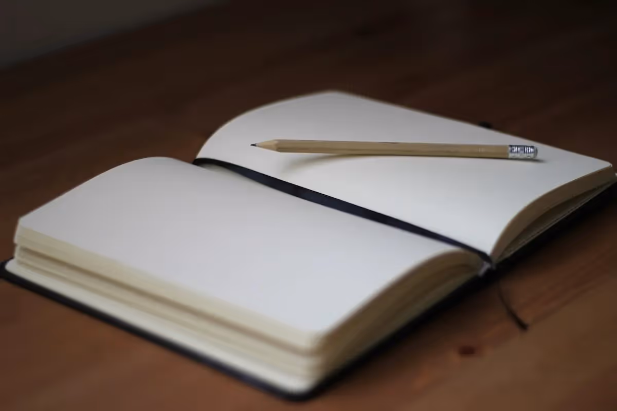Photo of an open notebook with a pencil resting on the pages