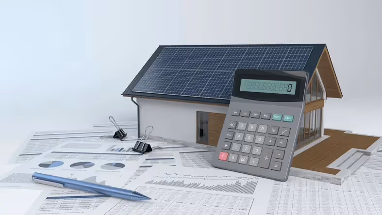 An image of a model house with solar panels and a calculator and papers next to it