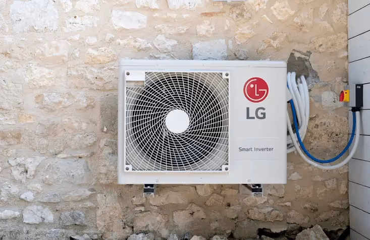 A LG heat pump that's wall mounted outside a home