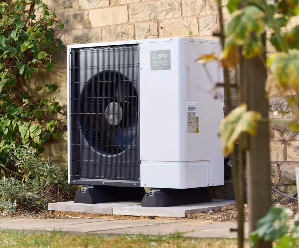 A mitsubishi ecodan heat pump positioned by a wall in a garden