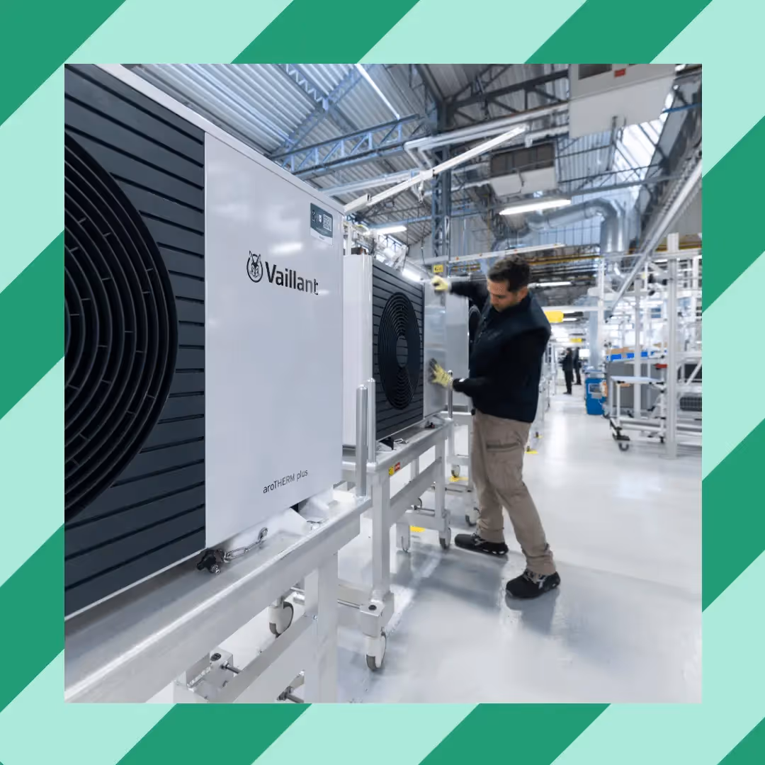 A stripy background with an image over it of a heating engineer working on a Vaillant heat pump in a factory