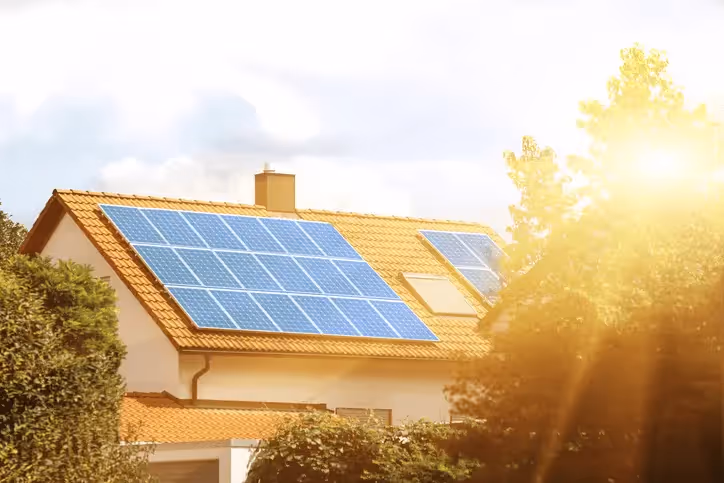 A house with solar panels with bright sunlight shining on it
