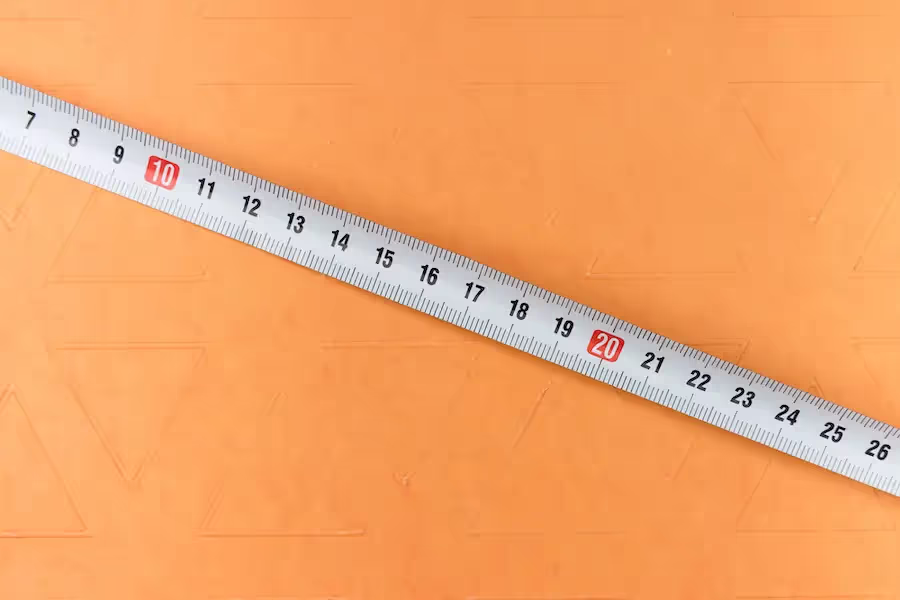 Photo of a metal tape measure against an orange background