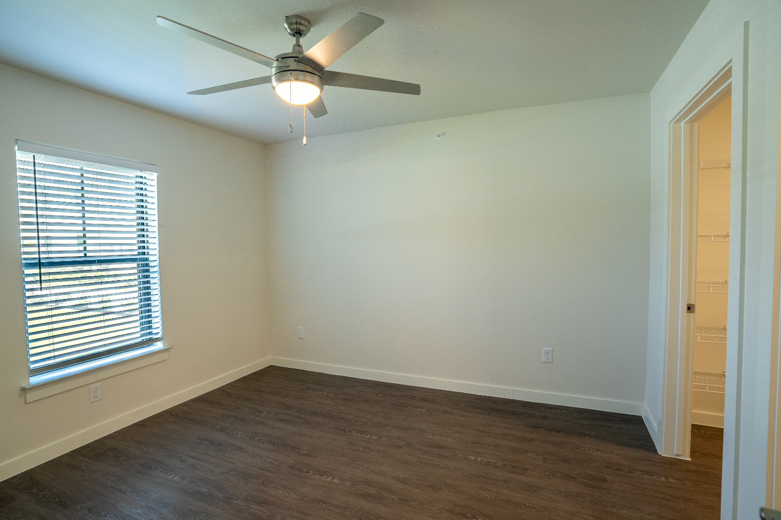 Unfurnished bed with large window and ceiling fan