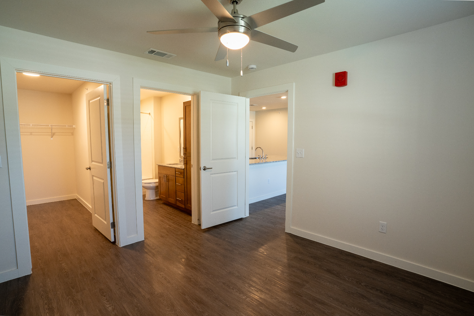 Unfurnished bed with large closet, ceiling fan and view of bathroom and kitchen