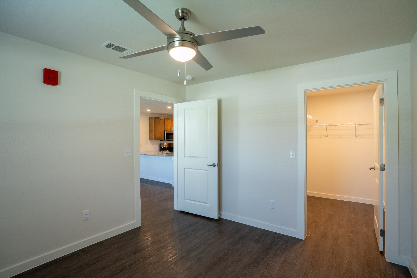 Unfurnished bed with large closet, ceiling fan and view of and kitchen