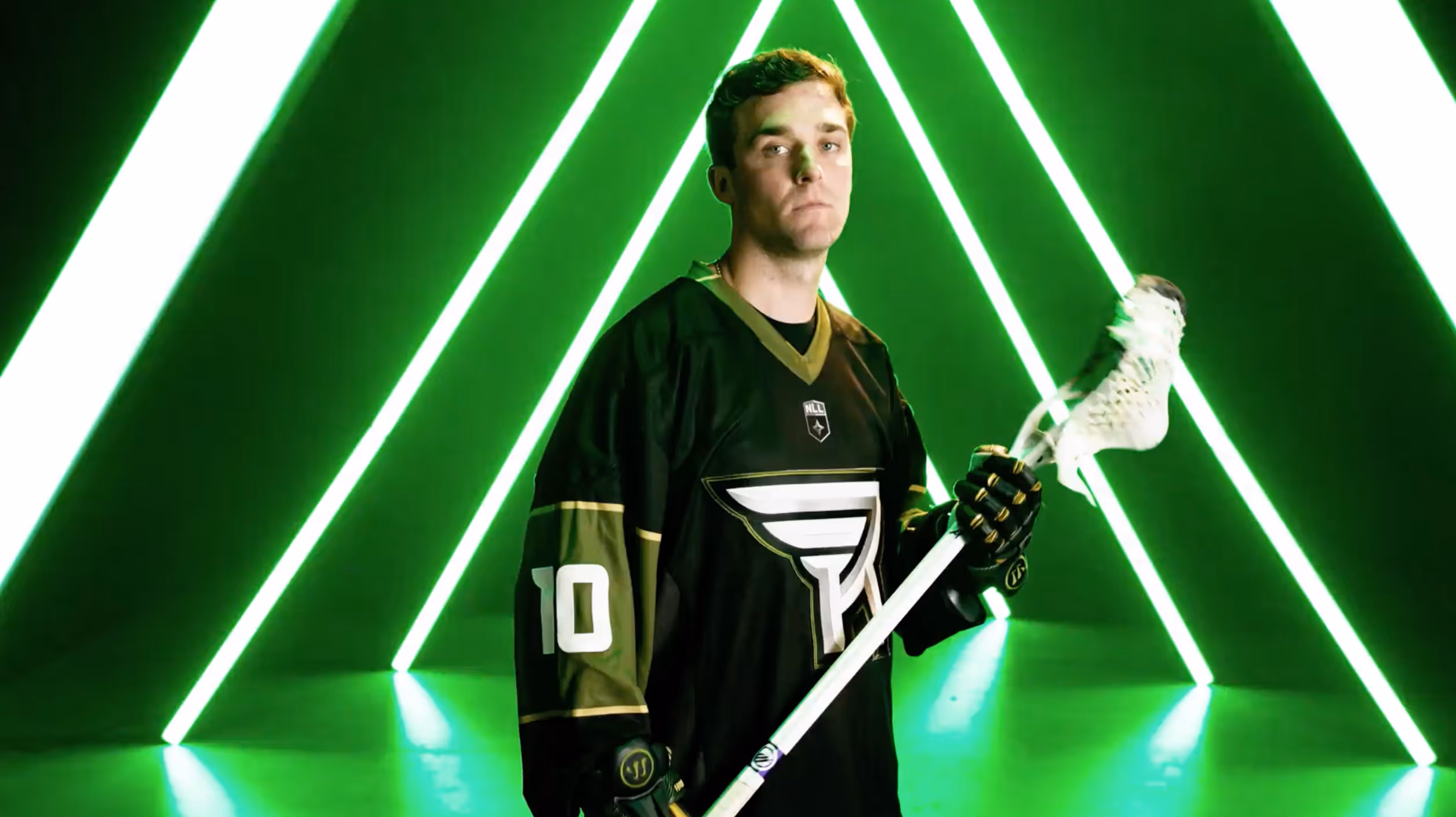 Lacrosse player wearing black jersey number 10 holding a lacrosse stick with neon green triangular lights behind.