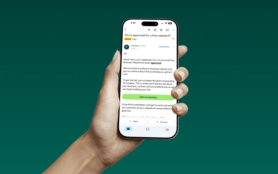 Hand holding a smartphone displaying an email approving a free business website application with a green button labeled 'Start my onboarding.'