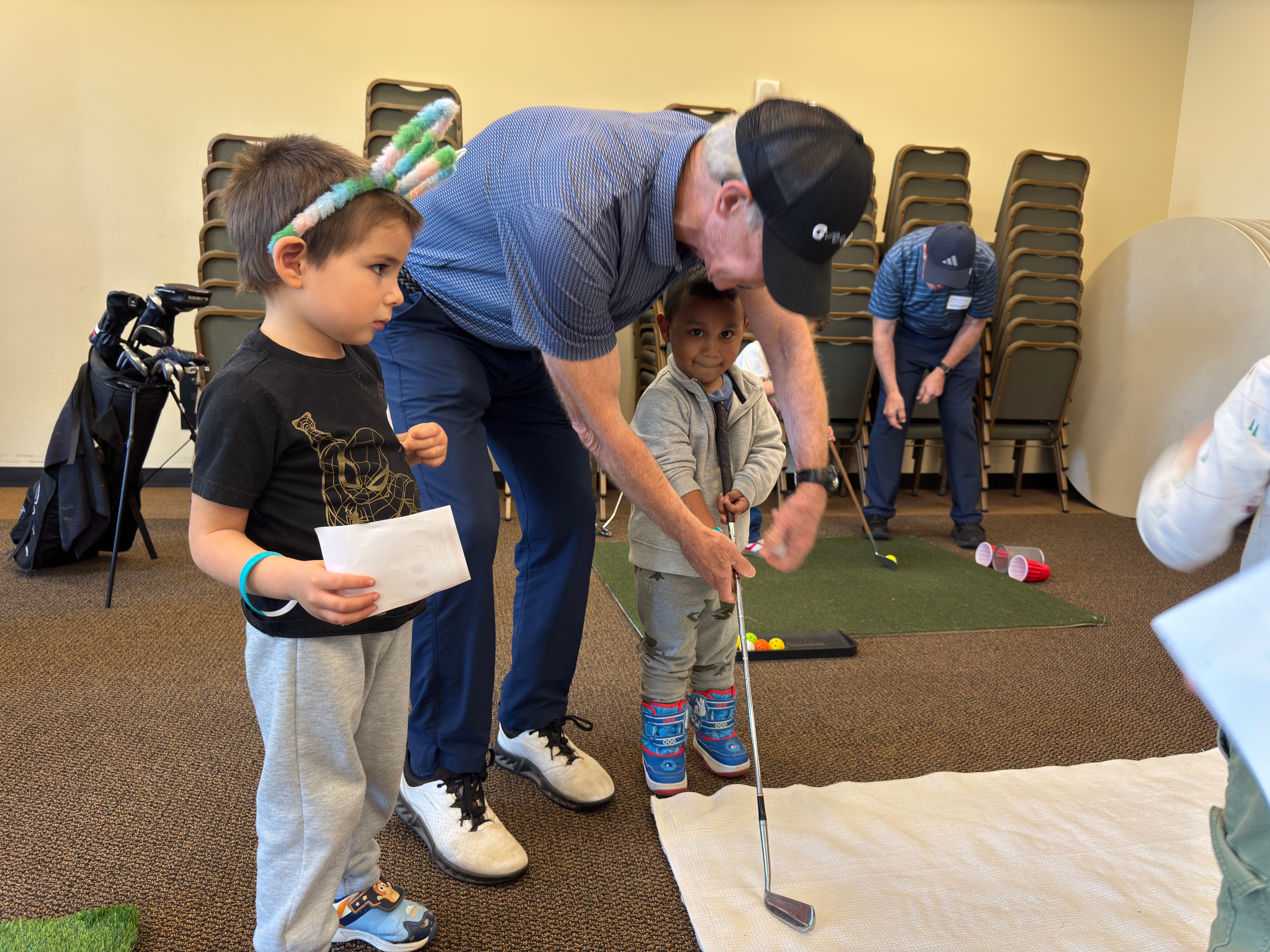 Group of five people indoors around a table, some sitting and some standing, engaged in conversation during a casual gathering.