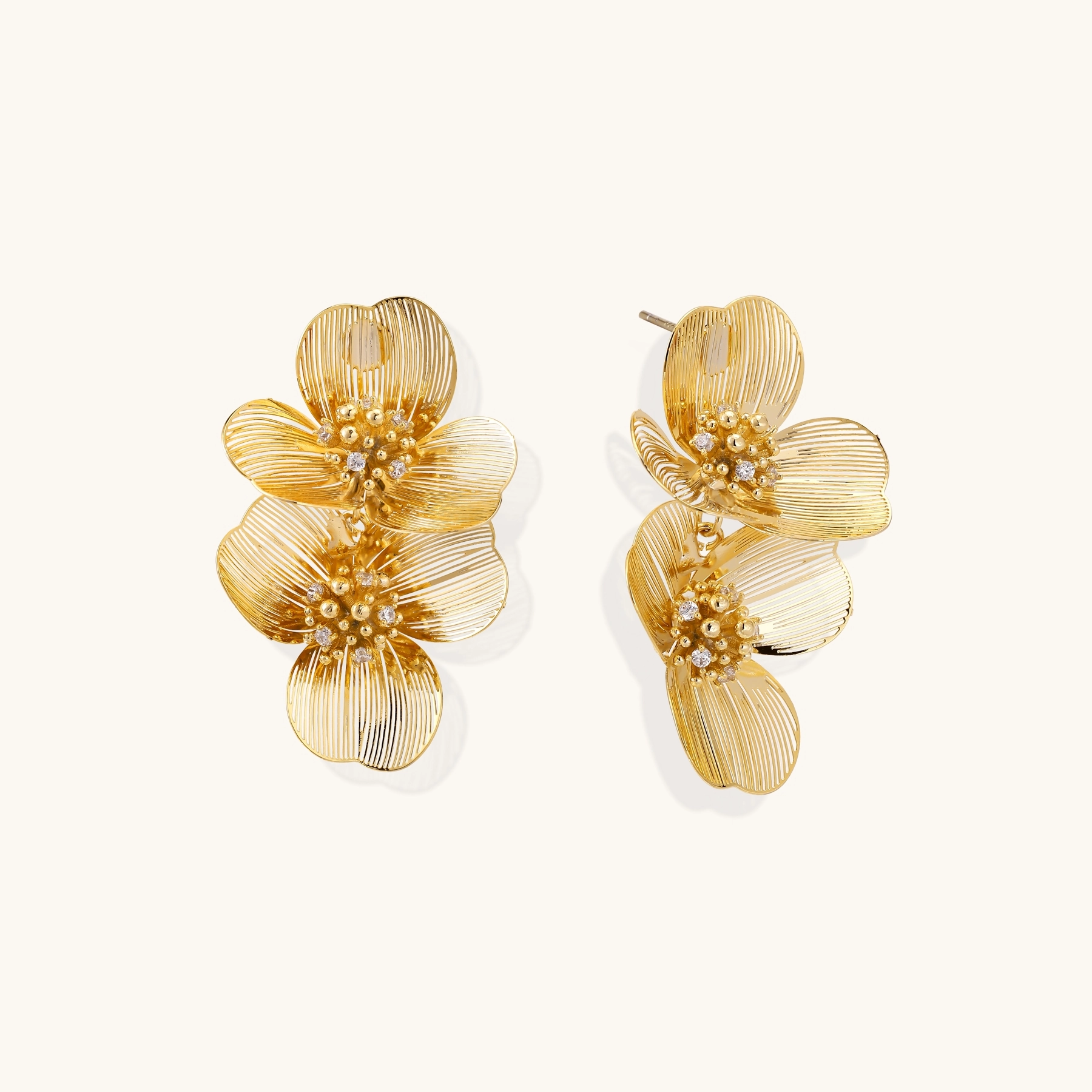 Pair of gold earrings shaped like two layered flowers with small gemstones in the center.