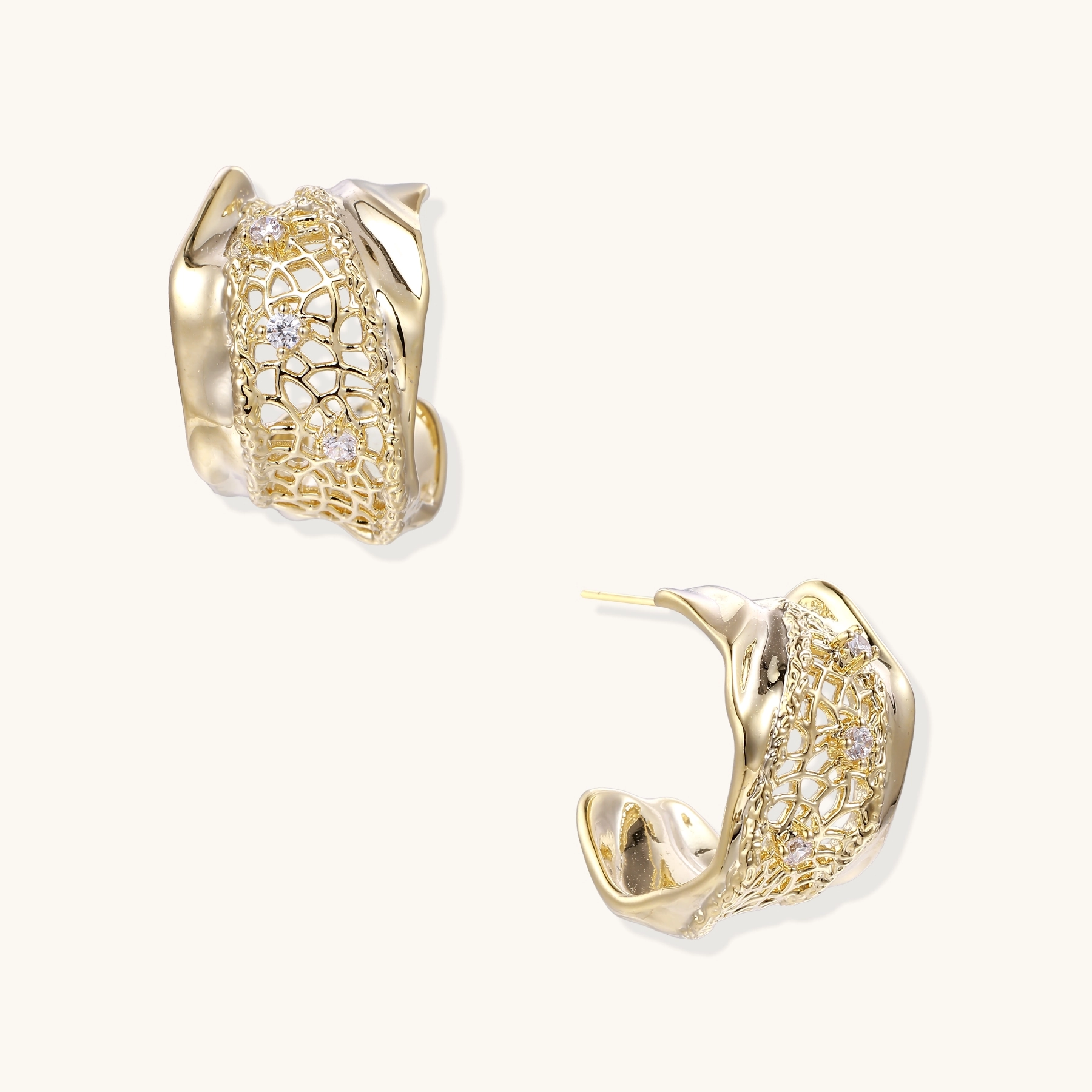 Pair of gold hoop earrings with intricate lattice design and small embedded clear gems on a light background.